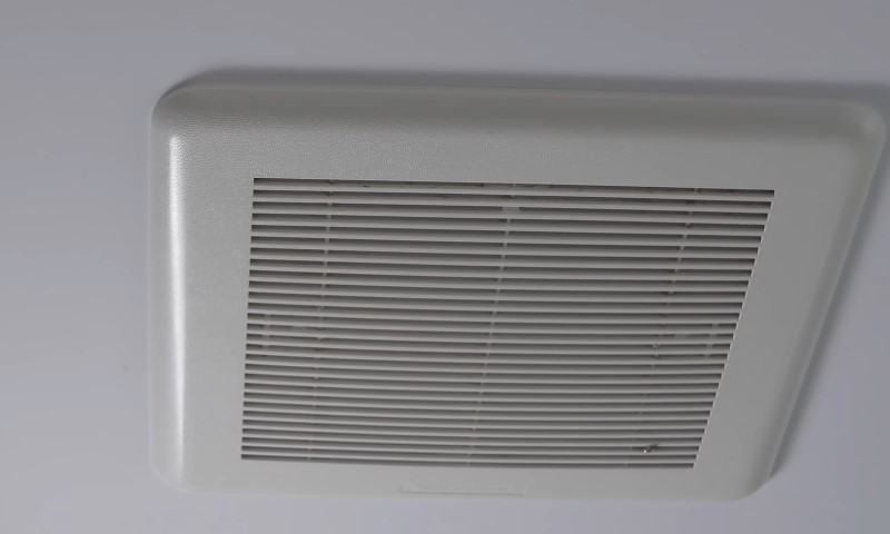 Ceiling-mounted, rectangular white exhaust fan cover with horizontal gray louvers