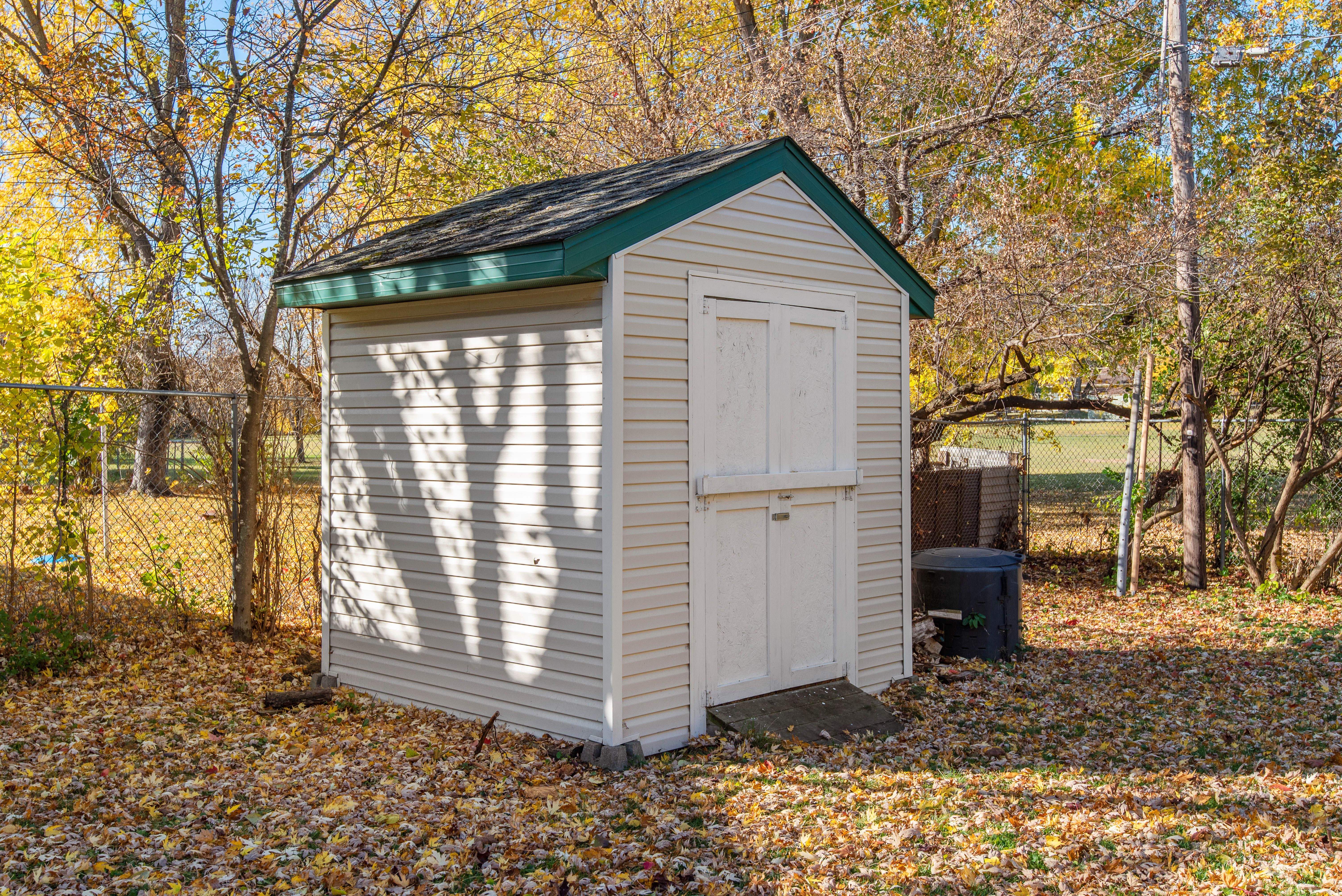 Small wooden backyard shed surrounded by foliage for attractive outdoor storage.